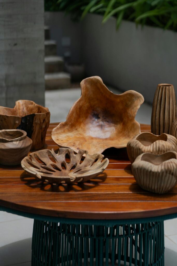 A collection of carved wooden decorative bowls and vases on an outdoor table.