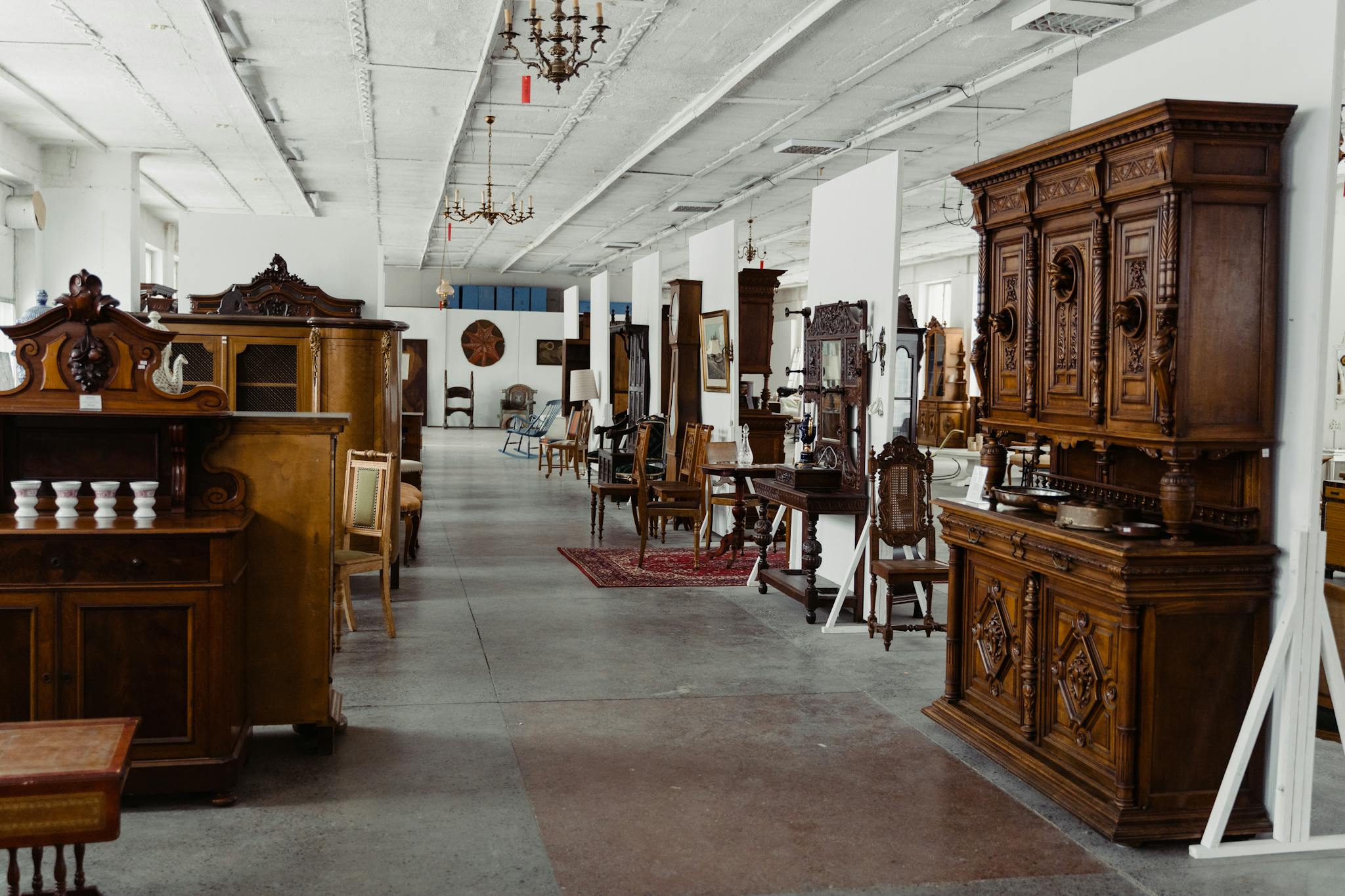 A spacious showroom filled with various antique wooden furniture pieces on display.