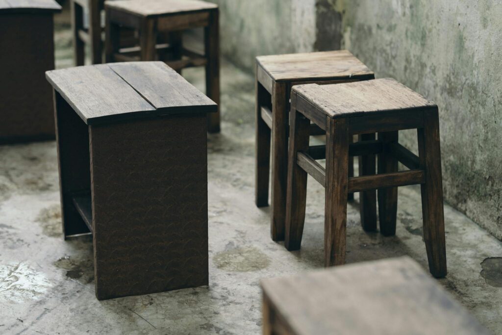 Rustic wooden chairs and tables in a weathered vintage interior, creating a nostalgic atmosphere.